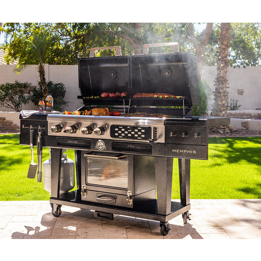 lifestyle_4, Black grill with silver accents and lettering with pit boss logo. Shot of grill in backyard while meats and veggies cook