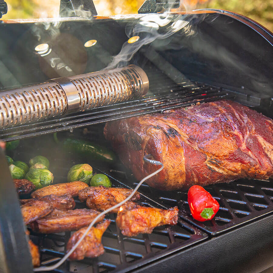 Smoking tube on tope grilling rack with meat and veggies on main grilling rack. Meat probe in meat.