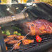 Smoking tube on tope grilling rack with meat and veggies on main grilling rack. Meat probe in meat.