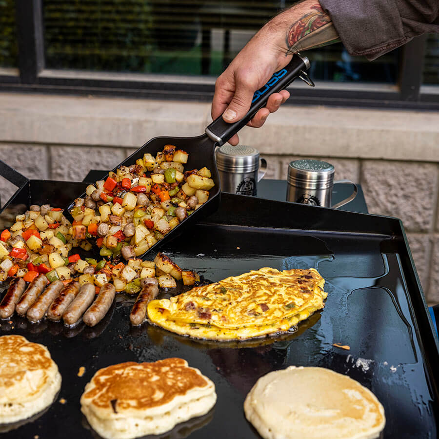 Griddle grub shovel scooping breakfast potatoes.