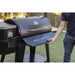 Man opening the table of the black grill outside in the grass.