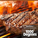 Up close of steak being seared in open flame on grill rack.