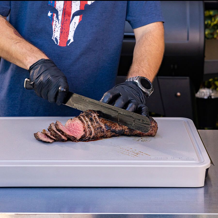 Close up of meat being cut on th board.