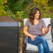 lifestyle_8, Black smoker with small Pit boss logo on transparent door and engraved "Pro Series" on front. Woman relaxing on porch with the smoker in the foreground