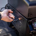 Close up of man holding the handlebar of the portable grill in the back of a truck.