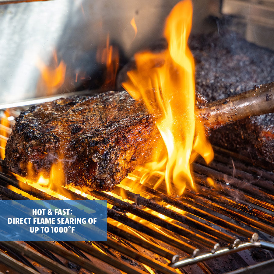 Up close view of meat being seared over a flame on the grill rack.