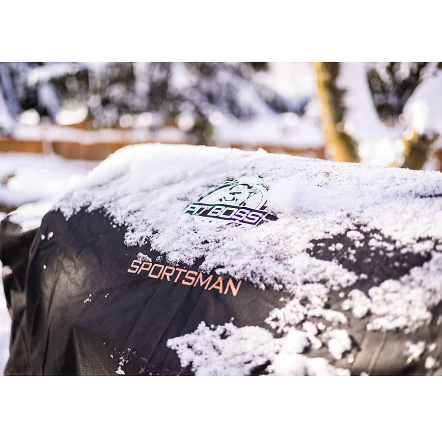 black and orange bbq grill cover outside in snow. detail shot of pit boss grills sportsman logo