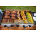 Overhead shot of meats and veggies cooking on griddle.