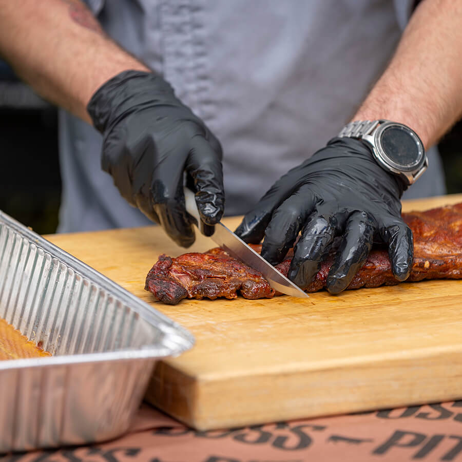 Close up of meat being sliced into pieces by sharp Pit Boss knife.