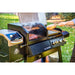 lifestyle_4, Silver and black grill with white lettering and Pit Boss logo. Person grilling meat on grill in sunny backyard