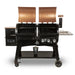 lifestyle_1, Black grill with brownish-orange/copper and silver accents with pit boss logo. Grill hoods open. Front angle view