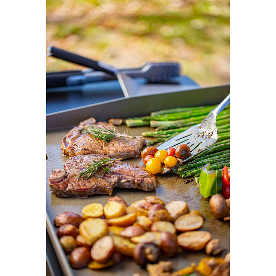 Up close of veggies and meats being cooked on the griddle.