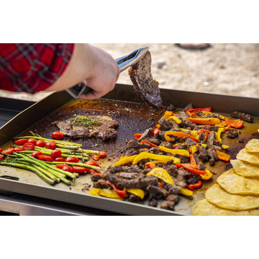 lifestyle of meat and veggies being cooked on griddle