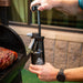 Close up of man pumping the spritz bottle over grill outside.