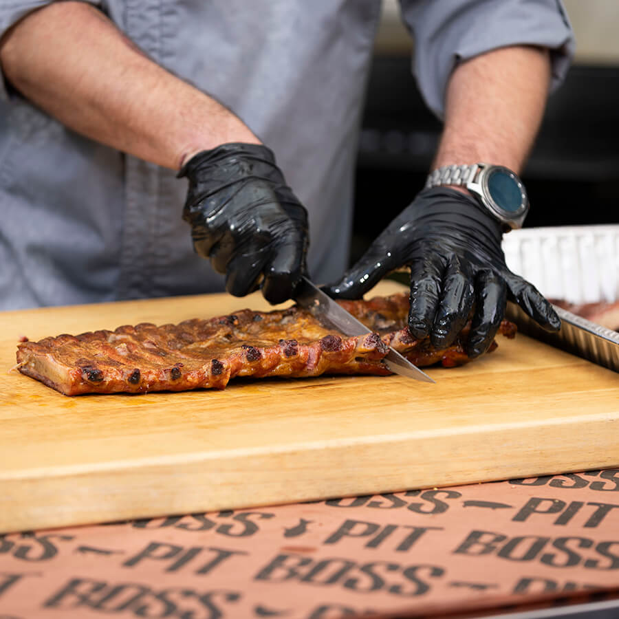 Close up of meat being sliced into pieces by sharp Pit Boss knife.