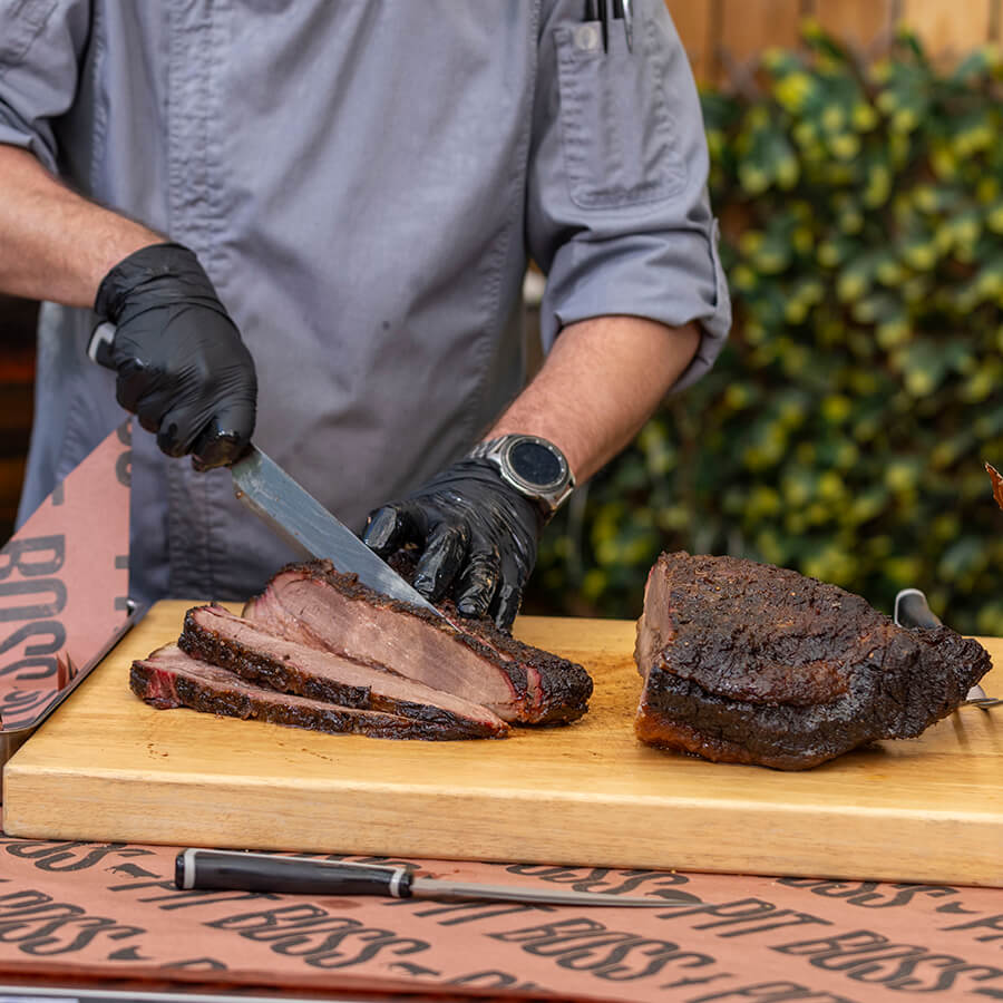 Close up of meat being sliced into pieces by sharp Pit Boss knife.