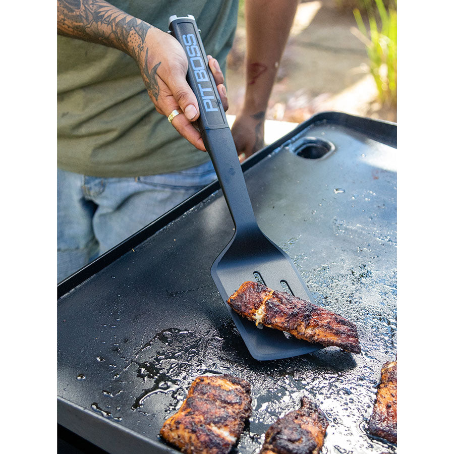 Spatula being used on griddle to flip meat.