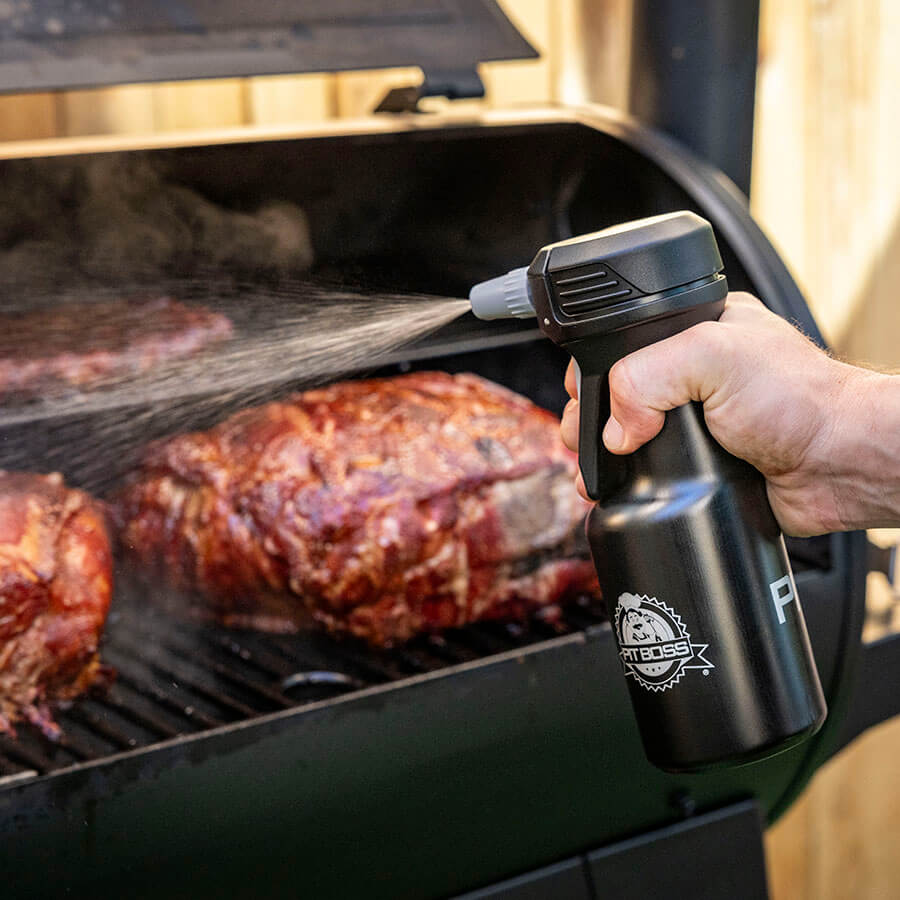 Close up of liquide being spritz onto meat in grill by the Pit Boss Spritz bottle.