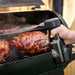 Close up of liquide being spritz onto meat in grill by the Pit Boss Spritz bottle.