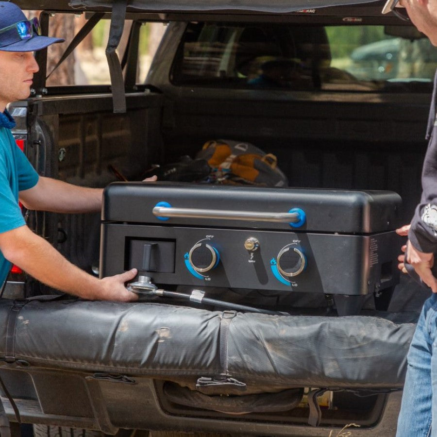 lifestyle_6, Black griddle with blue and silver accents. Large blue "Pit Boss" logo across front. Griddle being transported in back of truck