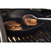 steaks searing in skillet on grill grates