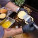 Close up of butter being brushed onto burger bun over top the griddle.