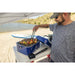 Man grilling on his portable grill cooking veggies and meats at a lake.