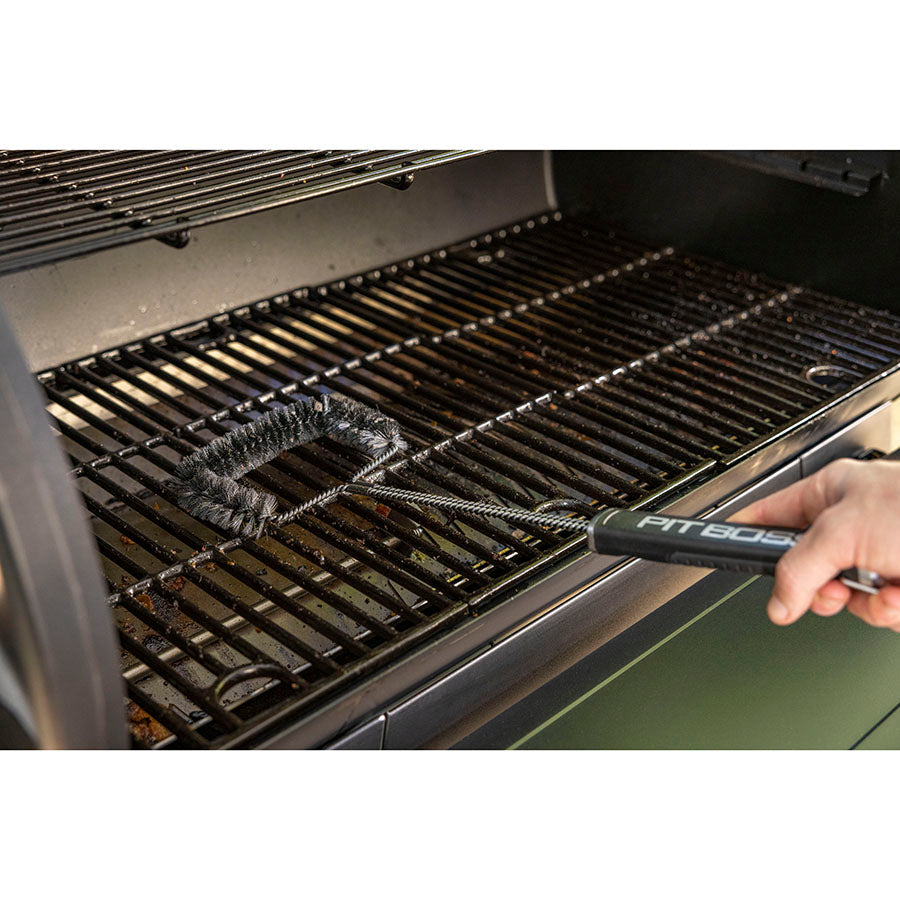 Close up of the extended wire cleaning brush being used on grilling racks to clean racks.