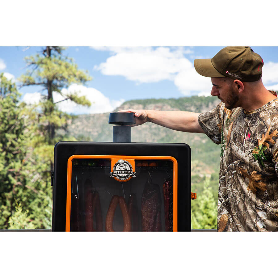 Smoker outside in a forest setting. Man adjusting the smoke stack.