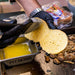 Close up of butter being brushed onto burger bun over top the griddle.