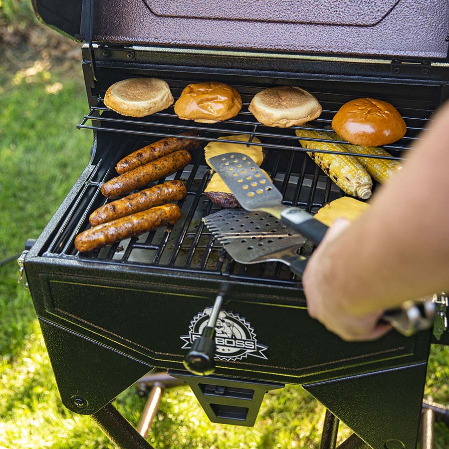 Food on grill with tongs in a backyard.