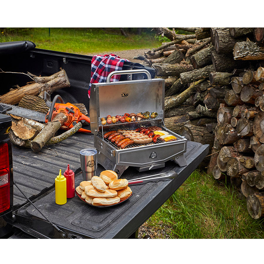 lifestyle_1, Silver/grey grill with black and white accents and small pit boss logo. Pictured on back of truck bed grilling meats and veggies