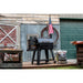 grill standing on porch in front of shed