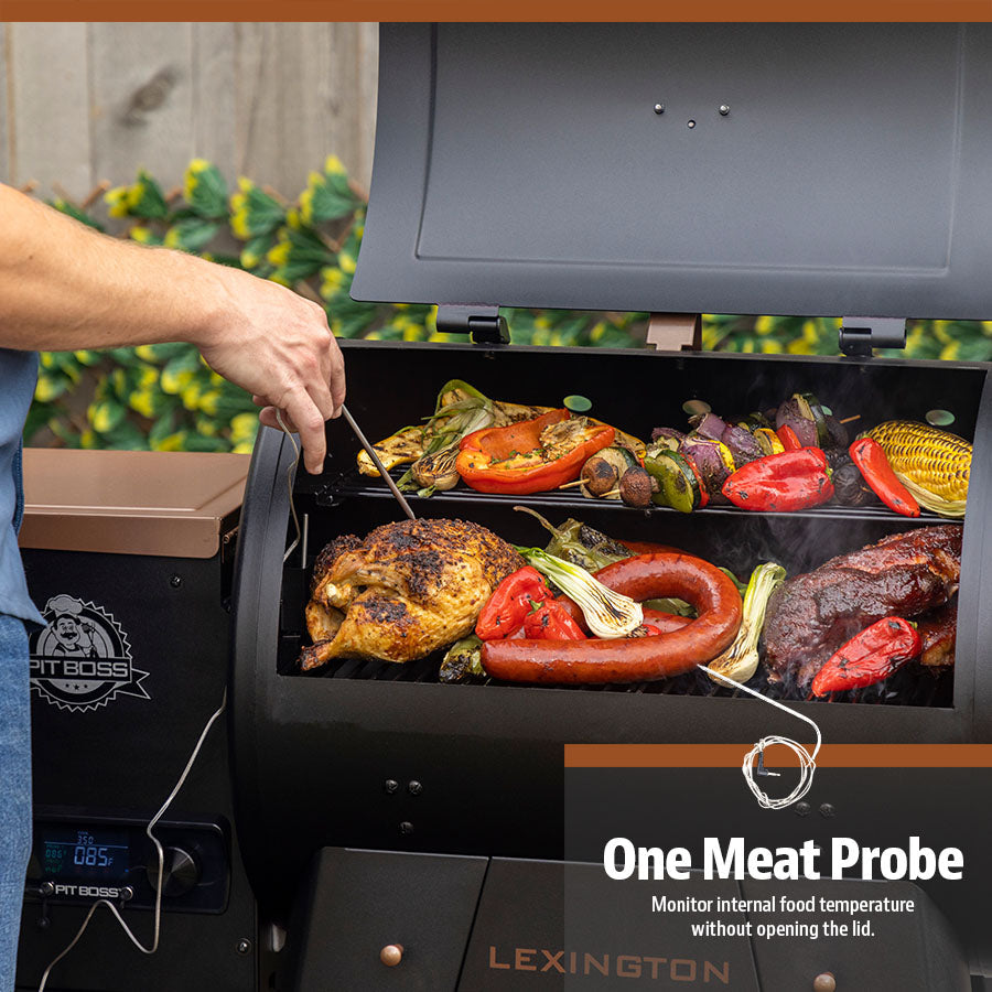 Meats and veggies grilling on both racks of the Pit Boss Wood Pellet Gril. Meat probe being used to check the temperature of the grilling meat.