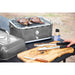 lifestyle_1, Grey grill with black and silver accents and small Pit Boss logo. Pictured on outdoor table withmeat grilling inside