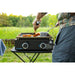 Front view of man using his portable griddle on a camping table making breakfast in the foest.